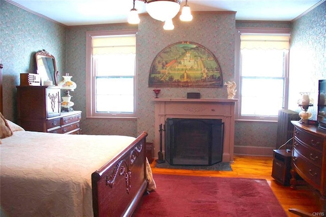 bedroom with a notable chandelier, ornamental molding, and dark wood-type flooring