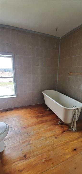 bathroom featuring hardwood / wood-style flooring, toilet, and tile walls