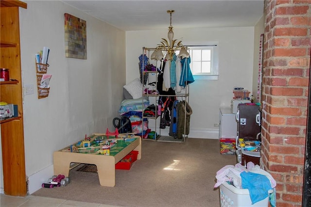 playroom featuring a notable chandelier, brick wall, and light colored carpet