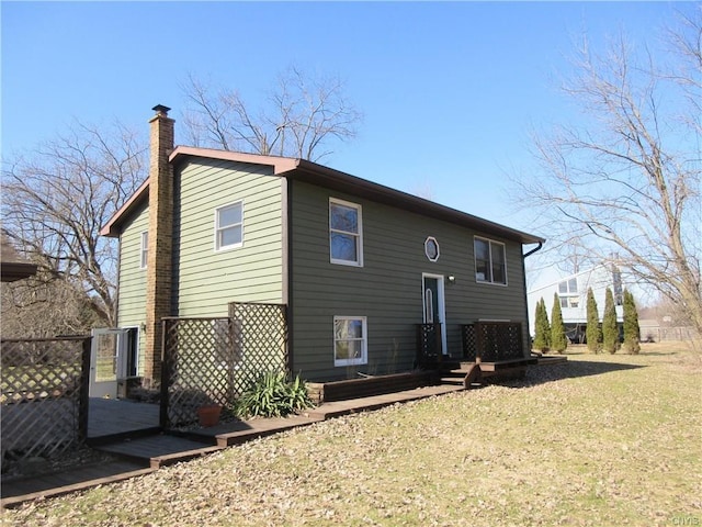 back of house with a wooden deck and a lawn