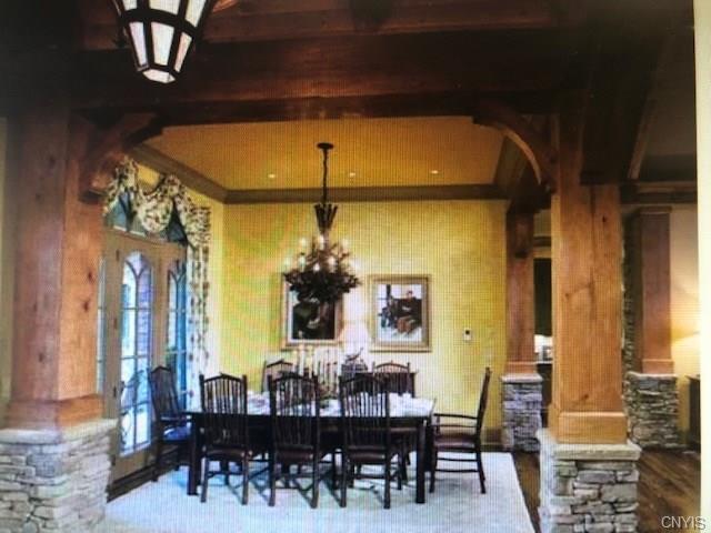 dining area featuring beam ceiling, dark wood-type flooring, an inviting chandelier, and ornate columns