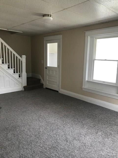 carpeted spare room featuring a drop ceiling