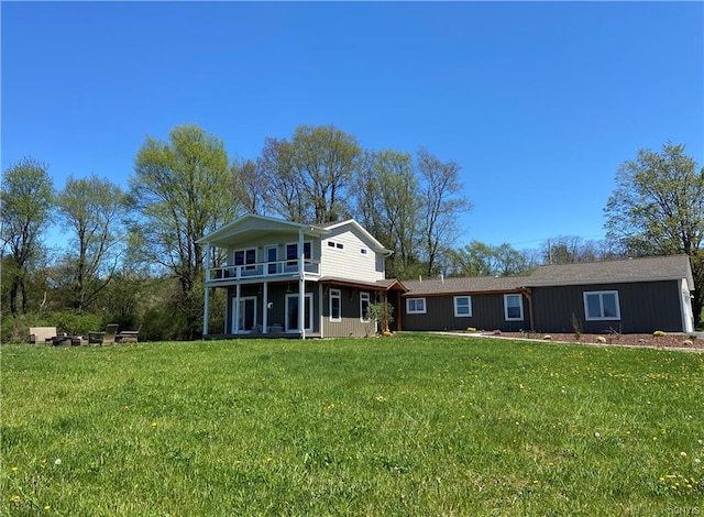 rear view of property featuring a balcony and a yard