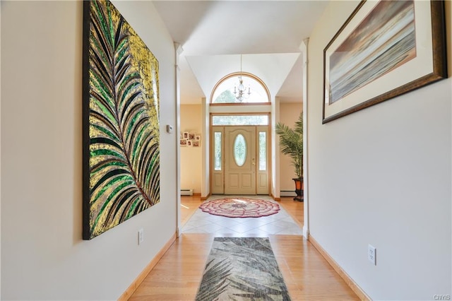 entryway featuring light tile floors, a notable chandelier, a baseboard heating unit, and vaulted ceiling