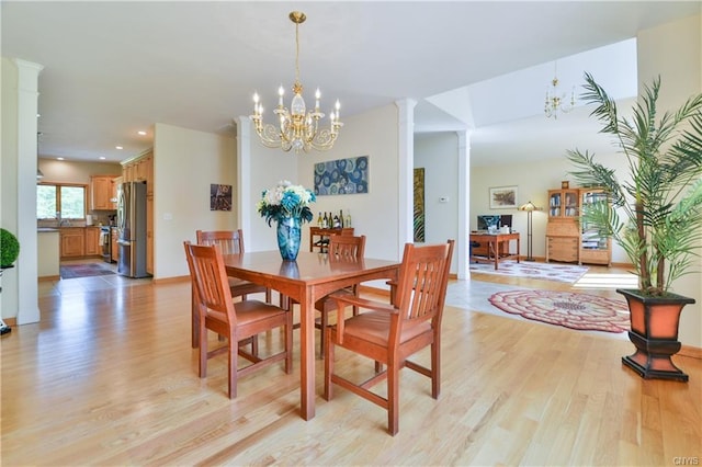 dining area featuring an inviting chandelier, decorative columns, and light hardwood / wood-style flooring