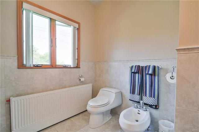 bathroom with radiator heating unit, plenty of natural light, a bidet, and tile walls