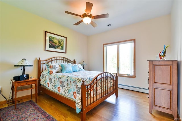 bedroom with light hardwood / wood-style floors, ceiling fan, and a baseboard radiator