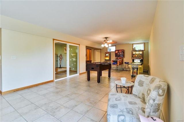 recreation room with ceiling fan, a baseboard heating unit, and light tile flooring