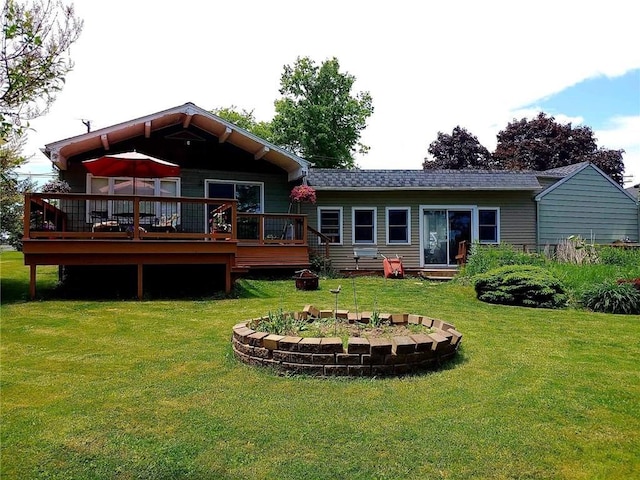 rear view of house with a wooden deck and a lawn