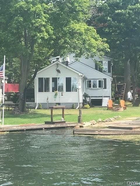 back of property with a water view and a yard