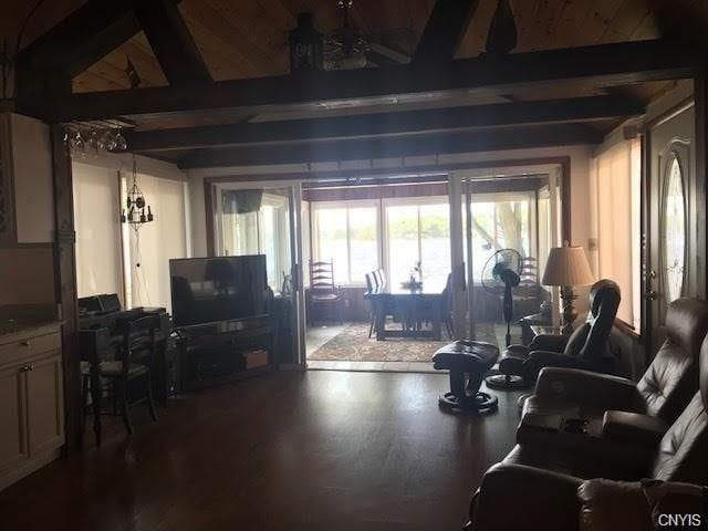 living room with a chandelier, dark hardwood / wood-style flooring, and beam ceiling