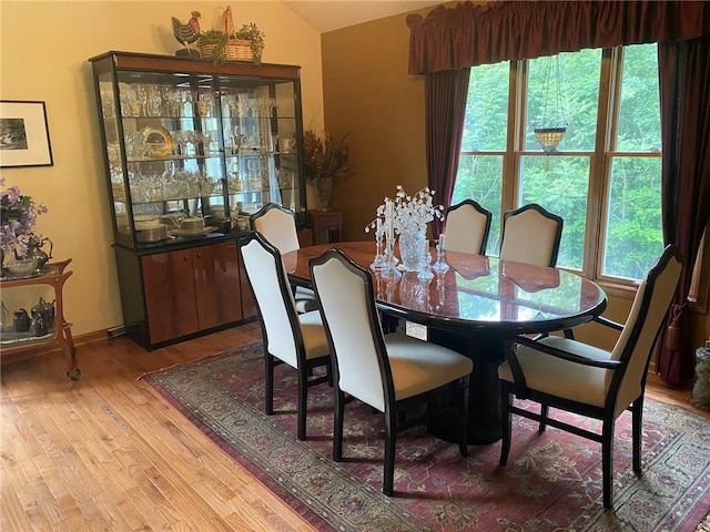 dining space with vaulted ceiling and light wood-type flooring