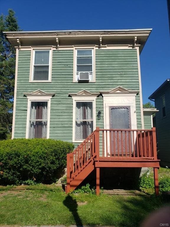 back of property with a wooden deck and a lawn