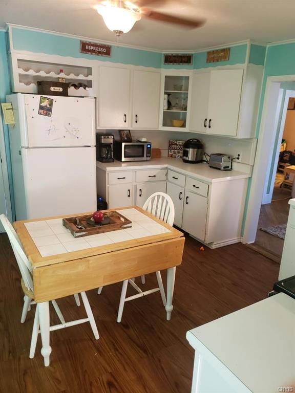 kitchen featuring dark wood-type flooring, white cabinetry, ceiling fan, and white fridge