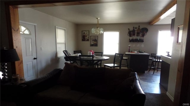 dining area with a notable chandelier, beam ceiling, and dark tile flooring