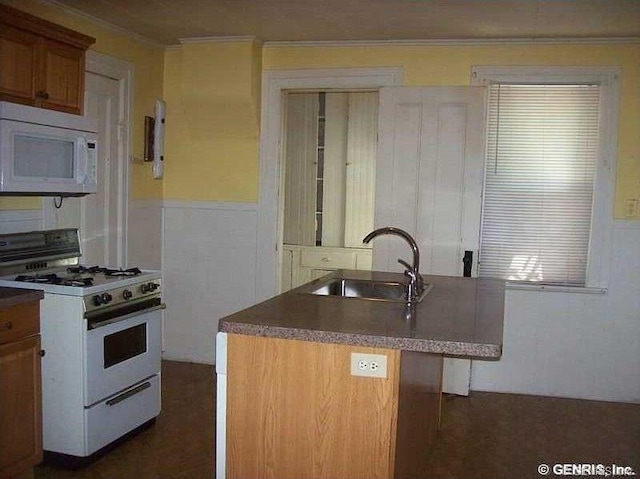 kitchen with white appliances, ornamental molding, sink, and a kitchen island with sink