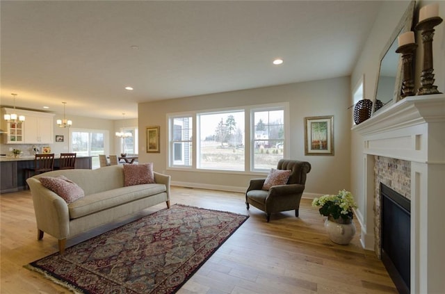 living room featuring an inviting chandelier, light hardwood / wood-style floors, and a healthy amount of sunlight