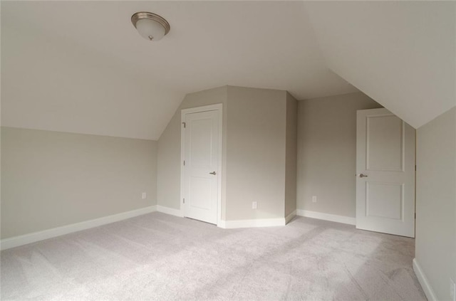 additional living space with light colored carpet and vaulted ceiling