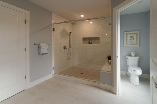 bathroom featuring a shower with door, tile floors, and toilet