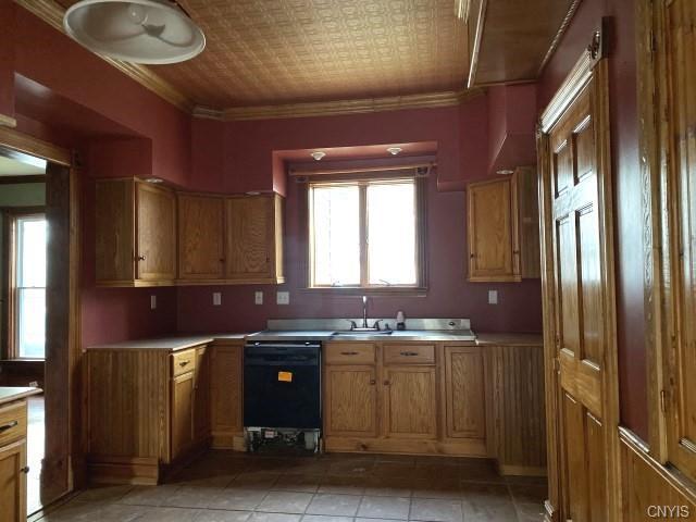 kitchen with crown molding, sink, light tile floors, and black dishwasher