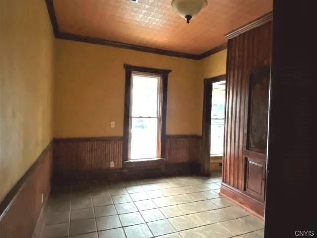 tiled empty room featuring ornamental molding