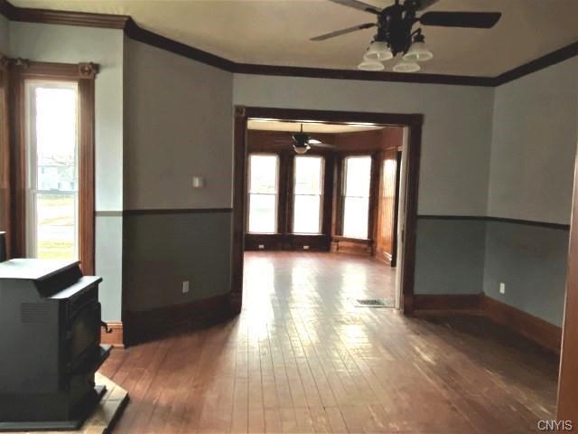 interior space with dark wood-type flooring, ceiling fan, and a wood stove