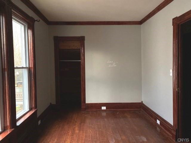 empty room with dark hardwood / wood-style flooring and crown molding