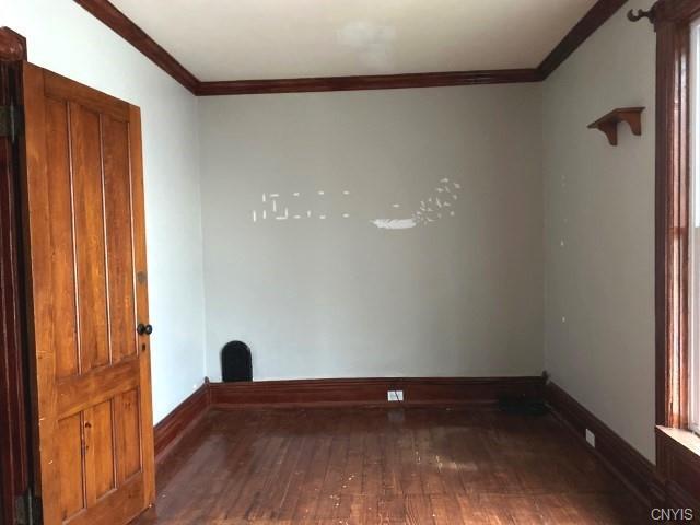 empty room featuring crown molding and dark hardwood / wood-style flooring