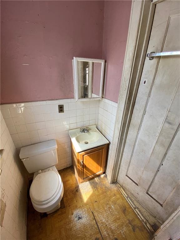 bathroom with tile walls, backsplash, toilet, and vanity