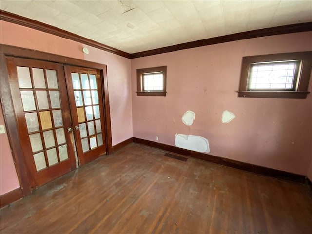 empty room featuring a healthy amount of sunlight, dark wood-type flooring, french doors, and crown molding