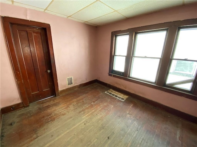 unfurnished room featuring dark hardwood / wood-style flooring and a paneled ceiling