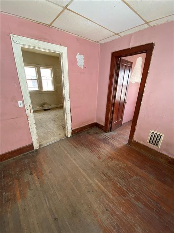 spare room with dark hardwood / wood-style floors and a drop ceiling