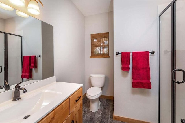 bathroom featuring hardwood / wood-style floors, toilet, walk in shower, and vanity