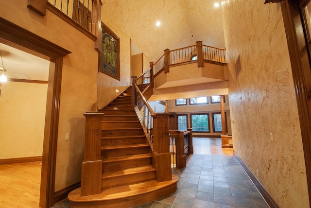 staircase with wood-type flooring and a high ceiling