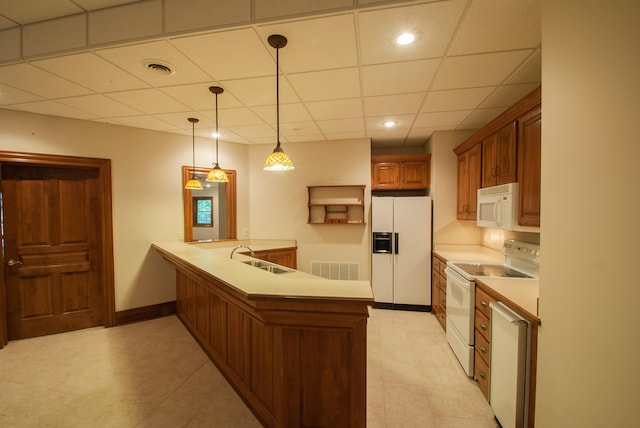 kitchen featuring sink, kitchen peninsula, white appliances, decorative light fixtures, and a drop ceiling