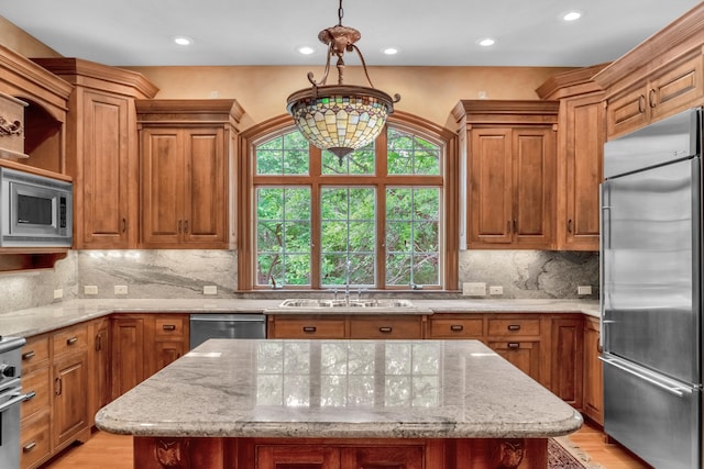 kitchen with decorative light fixtures, a notable chandelier, light stone counters, decorative backsplash, and built in appliances