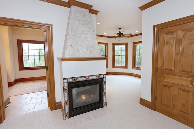 living room featuring ceiling fan, crown molding, a tile fireplace, and light carpet