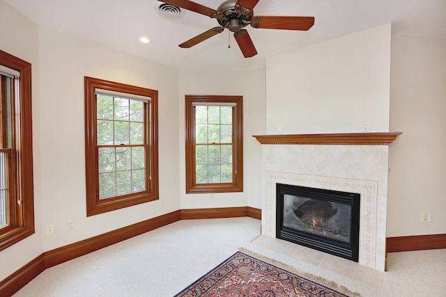 unfurnished living room with ceiling fan, carpet floors, and a tile fireplace