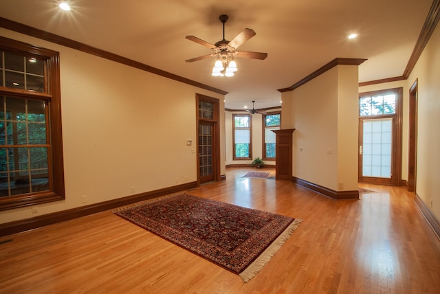 empty room with light hardwood / wood-style floors, ornamental molding, a wealth of natural light, and ceiling fan