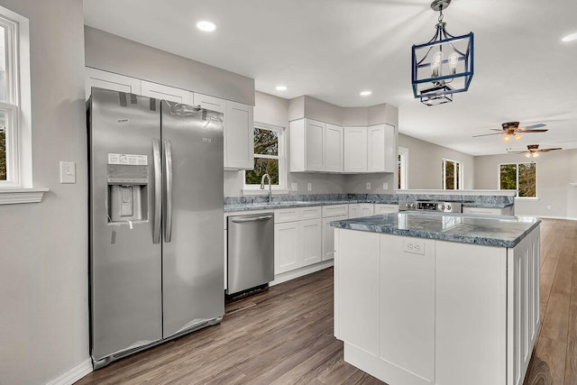 kitchen with appliances with stainless steel finishes, hardwood / wood-style flooring, decorative light fixtures, and white cabinets