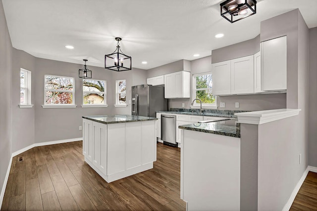 kitchen with a kitchen island, dark hardwood / wood-style floors, white cabinets, pendant lighting, and appliances with stainless steel finishes