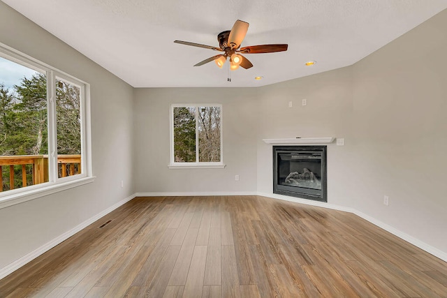 unfurnished living room featuring hardwood / wood-style flooring, a wealth of natural light, and ceiling fan