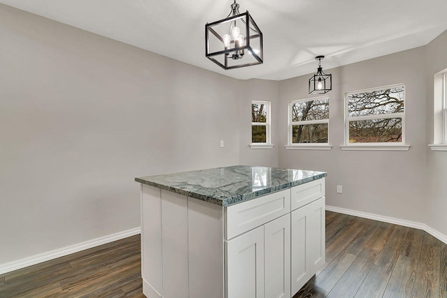 kitchen featuring white cabinets, a kitchen island, decorative light fixtures, dark hardwood / wood-style floors, and dark stone countertops