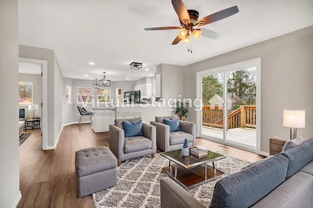 living room with ceiling fan with notable chandelier and hardwood / wood-style floors