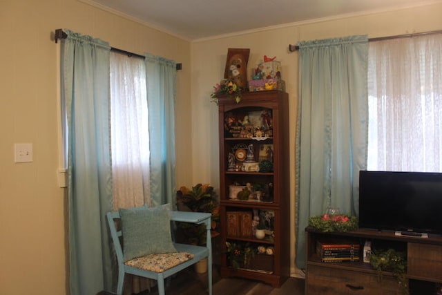 sitting room with ornamental molding and wood-type flooring