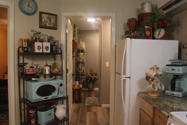 kitchen featuring white appliances, dark stone countertops, and wood-type flooring