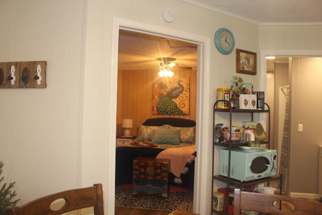 sitting room with wood walls, wood-type flooring, and crown molding