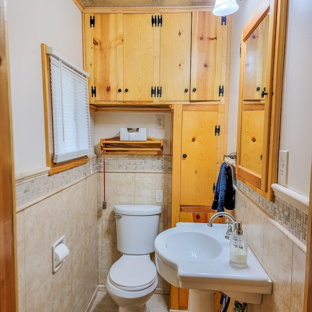 bathroom featuring sink, tile walls, and toilet