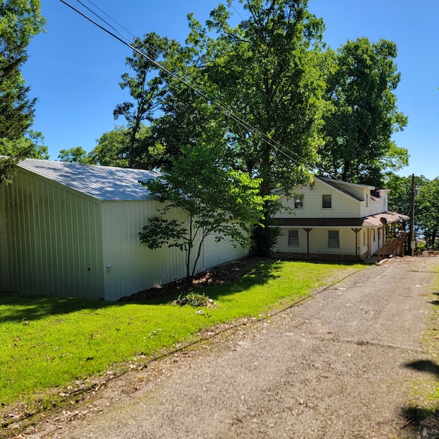 exterior space with dirt driveway, an outdoor structure, a yard, and a garage