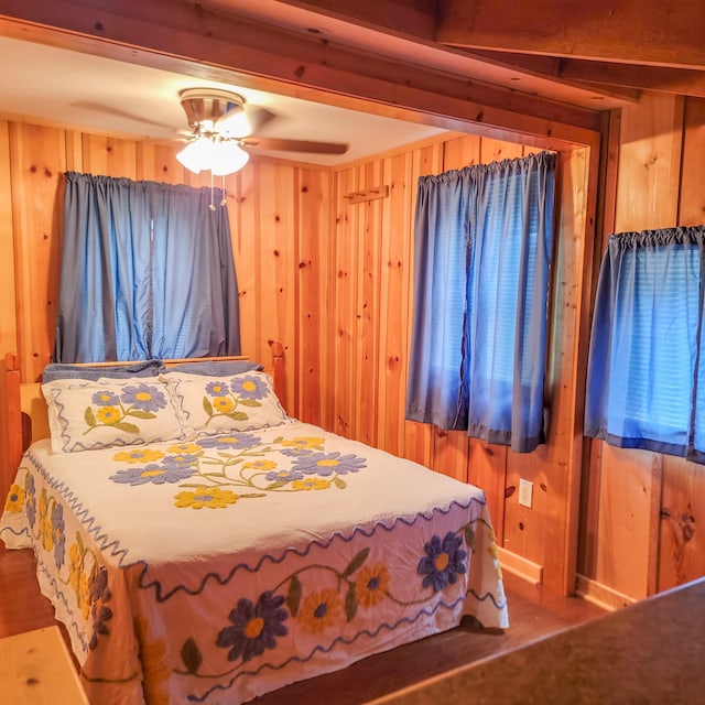 bedroom featuring wood walls, hardwood / wood-style floors, and ceiling fan